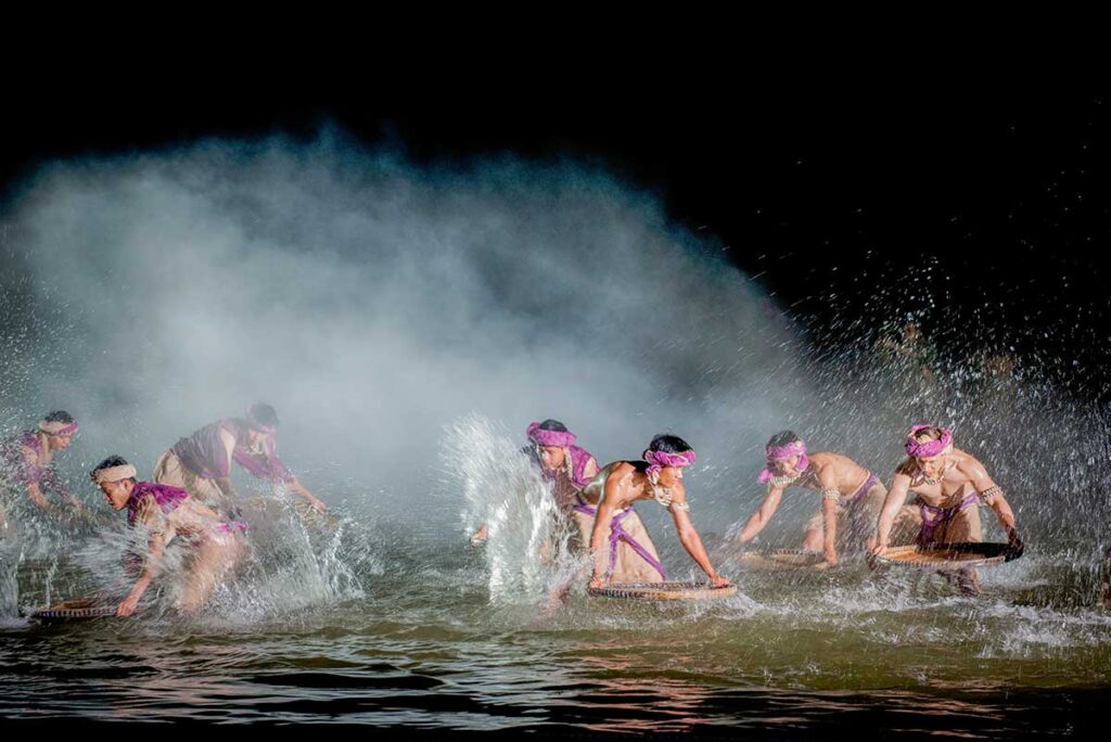 Dancers performing a dramatic water scene under mist and lighting effects at the Hoi An Memories Show.