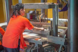 Woman demonstrating silk weaving on a traditional wooden loom at Hoi An Silk Village.