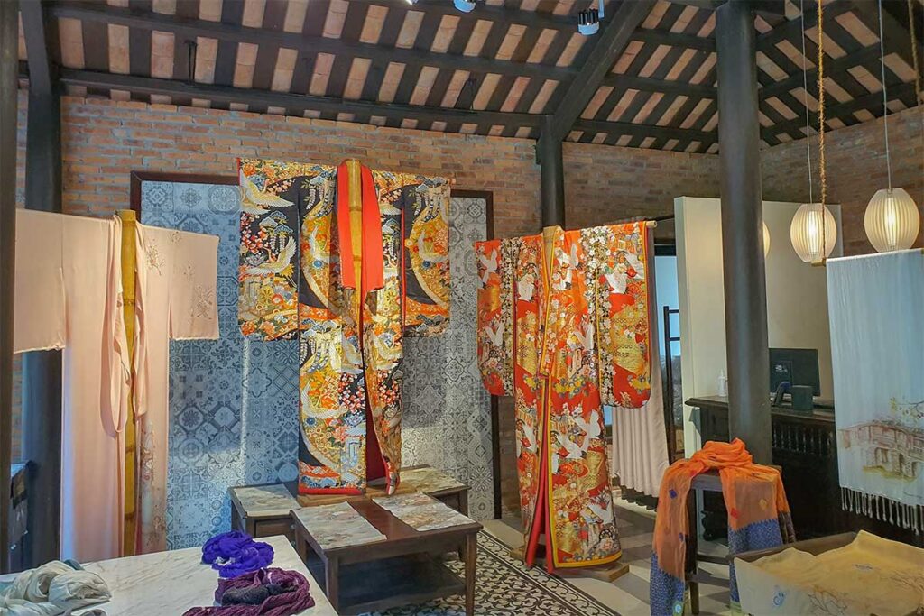 Traditional silk garments on display in Hoi An Silk Village, featuring colorful embroidered robes and handwoven textiles.