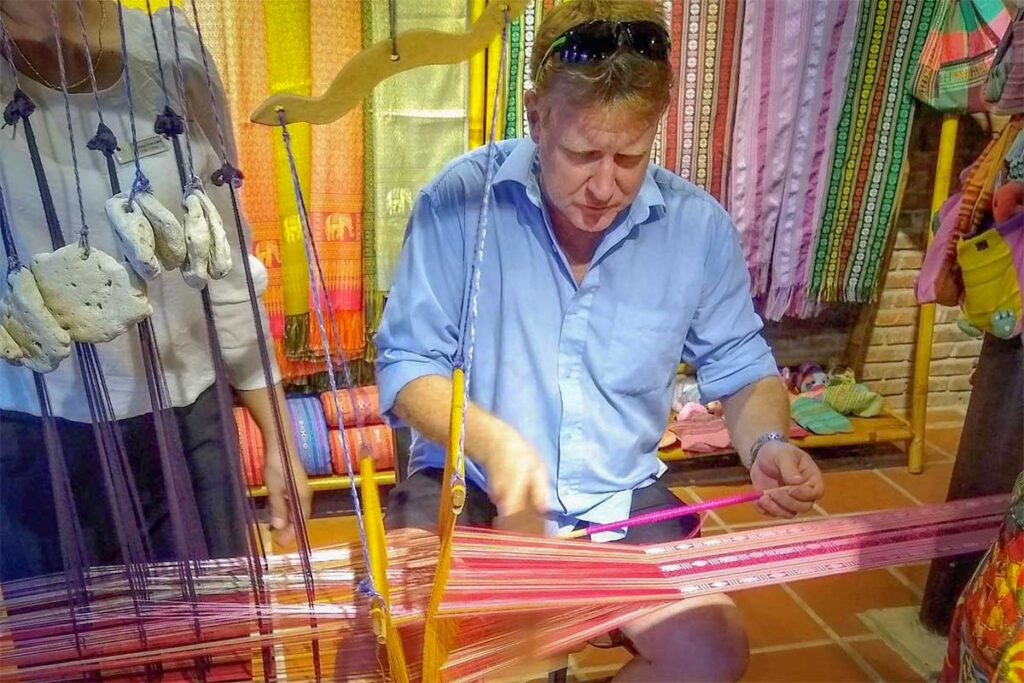 Tourist trying handloom weaving at Hoi An Silk Village in Hoi An, Vietnam.