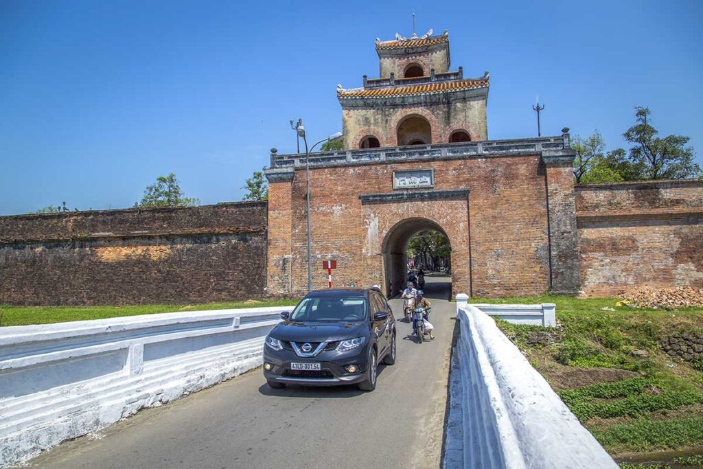 A Hue car rental with driver is driving outside one of the gates of Hue Imperial Citadel