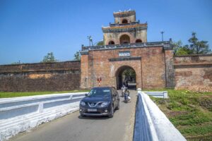 A Hue car rental with driver is driving outside one of the gates of Hue Imperial Citadel