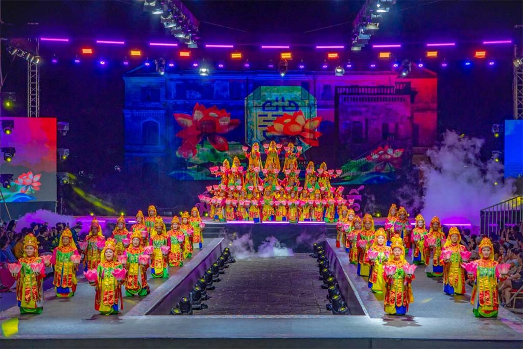 A large stage where dozens of artists in traditional clothing perform during the Hue Festival