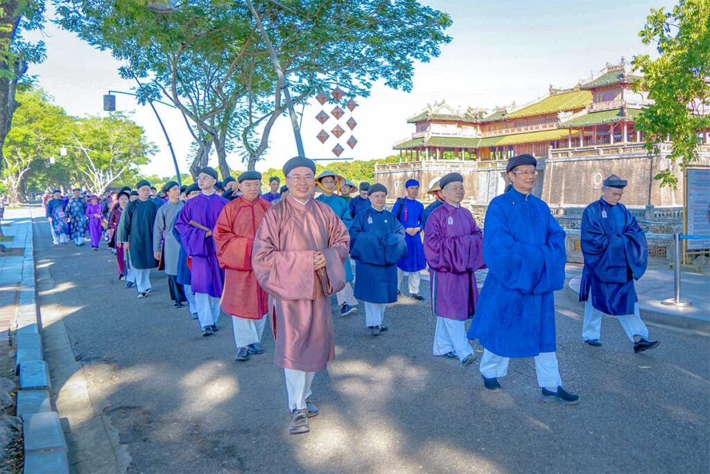 People traditional   dressed walking in lines in front of the main gate of Hue Imperial Palace during a historical event during Hue Festival