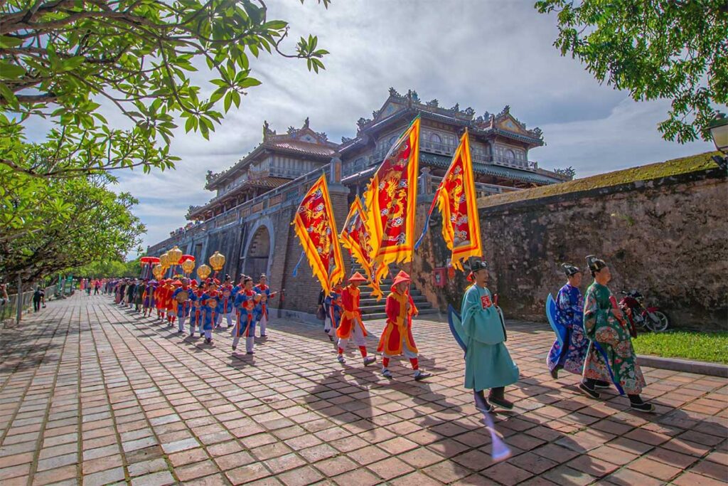 Flag carrying ceremony by people in traditional clothes in front of the main gate of Hue Imperial City during Hue Festival 