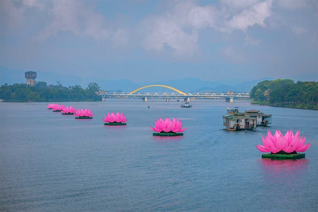 The Perfume River with lotus stages floating and dragon boats passing by during Hue Festival