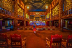 Red chairs, a stage and a throne viewing area inside the Hue Royal Theatre part of The Forbidden Purple City within Hue Imperial City