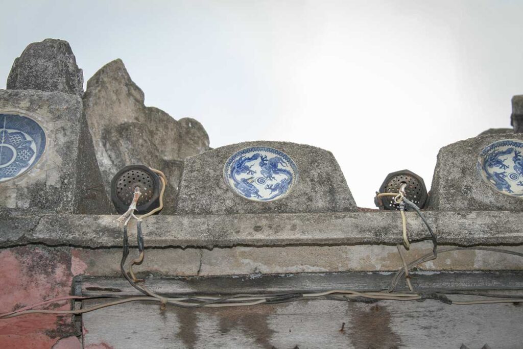Ceramic inlays on Japanese Bridge Hoi An – Close-up of traditional blue-and-white porcelain plates embedded in the ancient bridge’s walls, a detail showcasing Hoi An’s fusion of Vietnamese, Japanese, and Chinese craftsmanship.