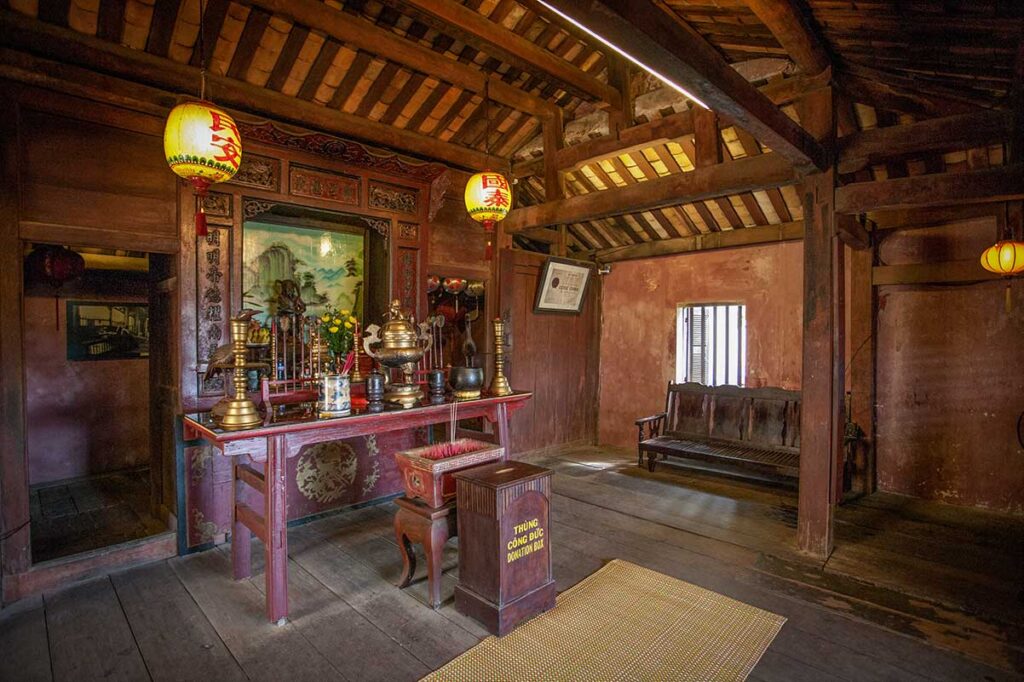 Worship altar inside Japanese Bridge Hoi An – A traditional wooden altar with brass incense burners and lanterns inside the Japanese Bridge, showcasing the spiritual atmosphere of this UNESCO landmark.