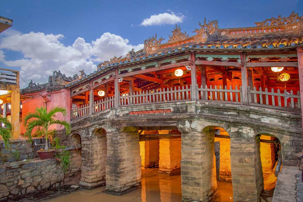 Japanese Covered Bridge Hoi An at dusk – iconic landmark illuminated with lanterns, reflecting on the Thu Bon River, one of Hoi An’s top attractions.