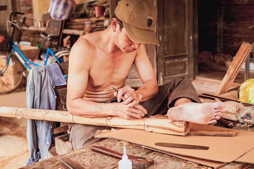 Craftsman carving bamboo with precision at Kim Bong Carpentry Village on Cam Kim Island.