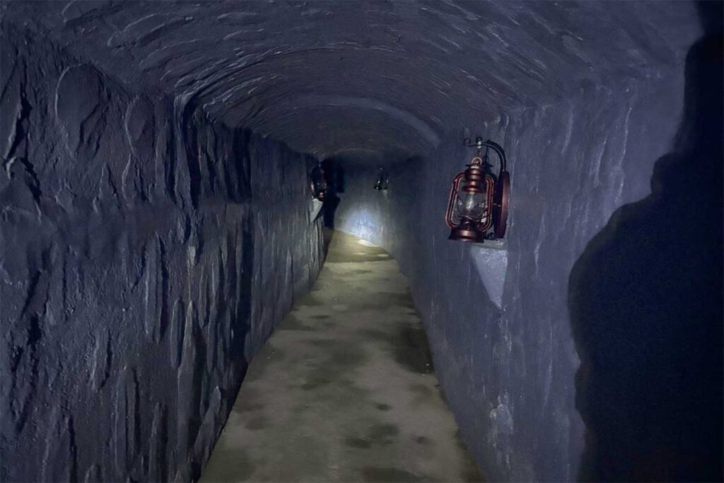 Narrow underground passage of Ky Anh Tunnels lit by lanterns, showing how soldiers moved unseen during the war.