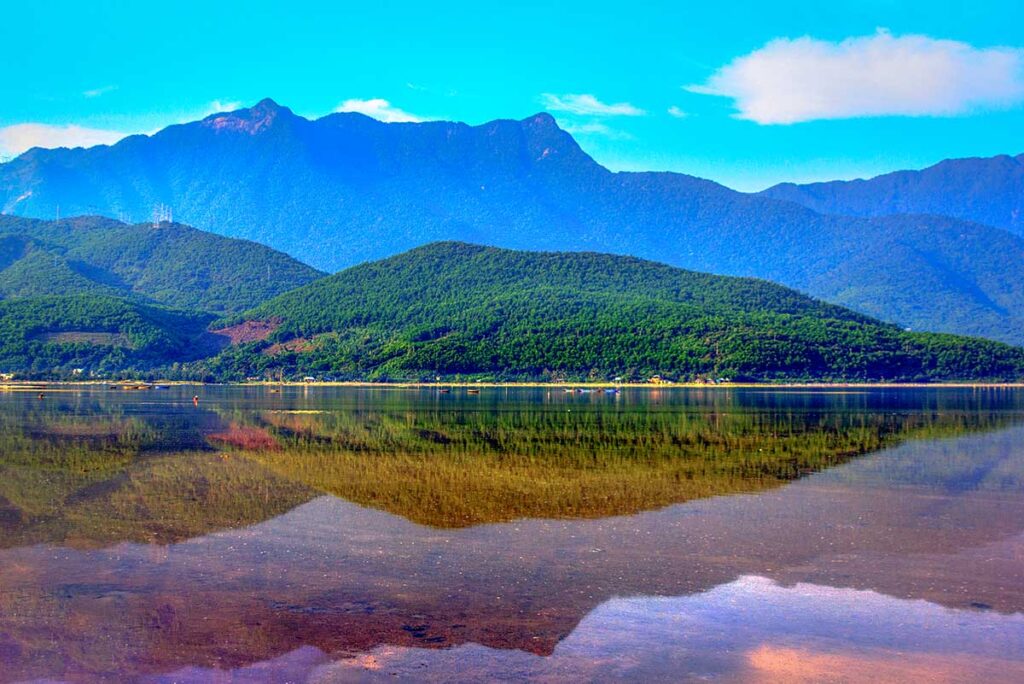 Surrounding forest and mountains reflecting on the water of Lap An Lagoon 