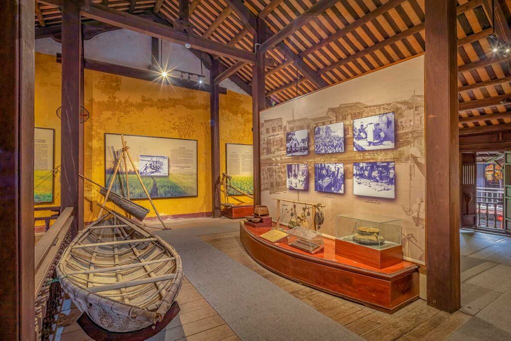 Fishing culture display at the Museum of Folk Culture in Hoi An with a woven bamboo basket boat and tools set against interpretive panels
