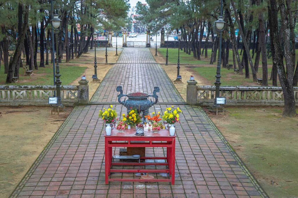 A small altar with bronze incense burner overlooking a straight stone path through a park called Nam Giao Esplanade