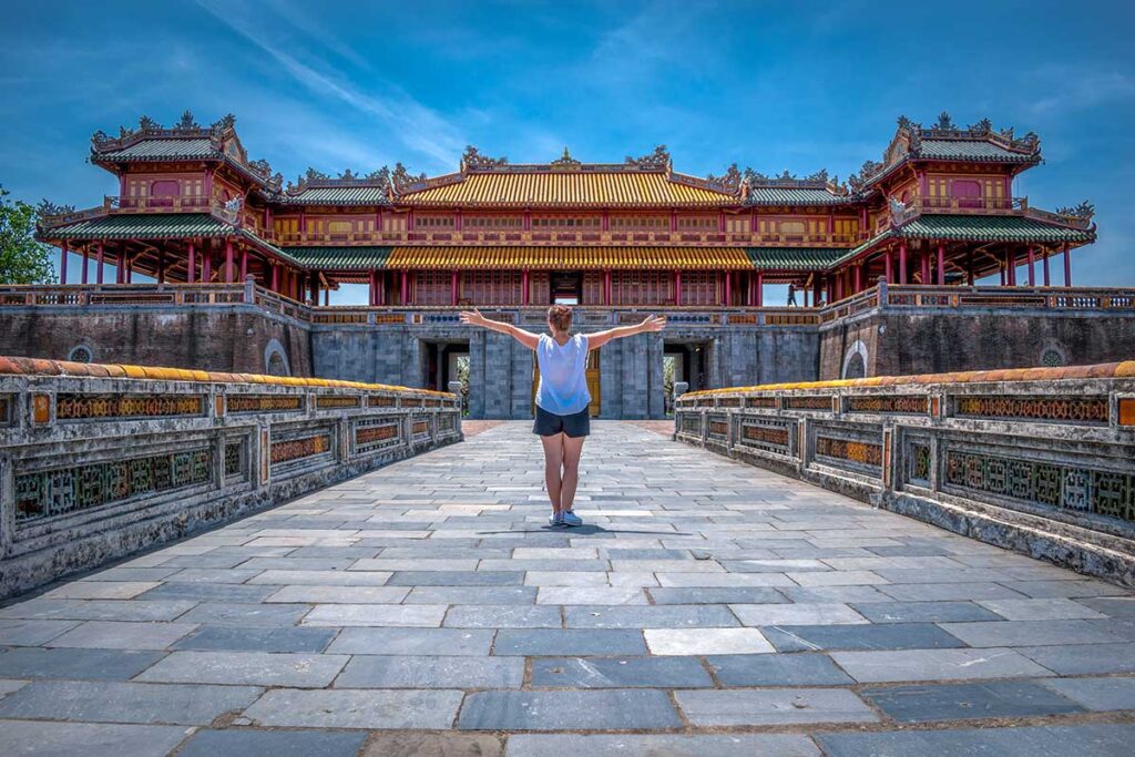 A woman standing on the stone bridge with Ngo Mon Gate in the background - the gate of the Imperial City