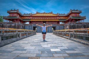 A woman standing on the stone bridge with Ngo Mon Gate in the background - the gate of the Imperial City