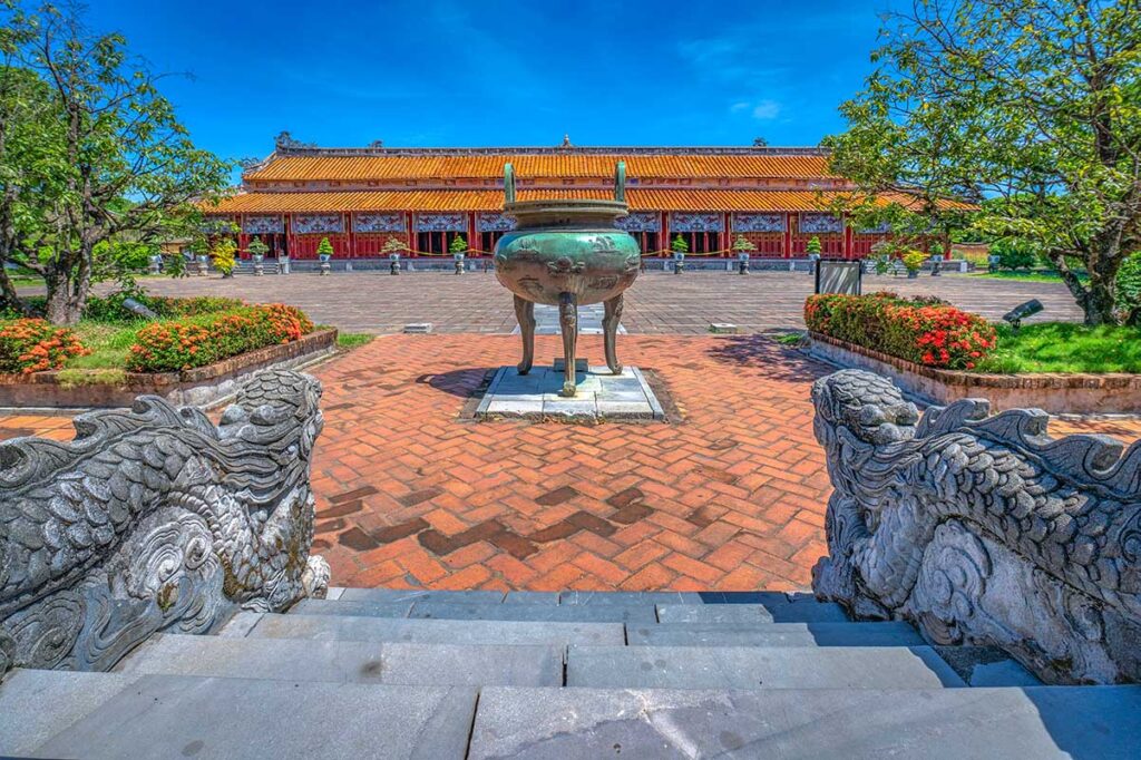One of the main Nine Dynasty Urns seen from Hien Lam Pavilion looking out in the courtyard with in the back The To Mieu Temple