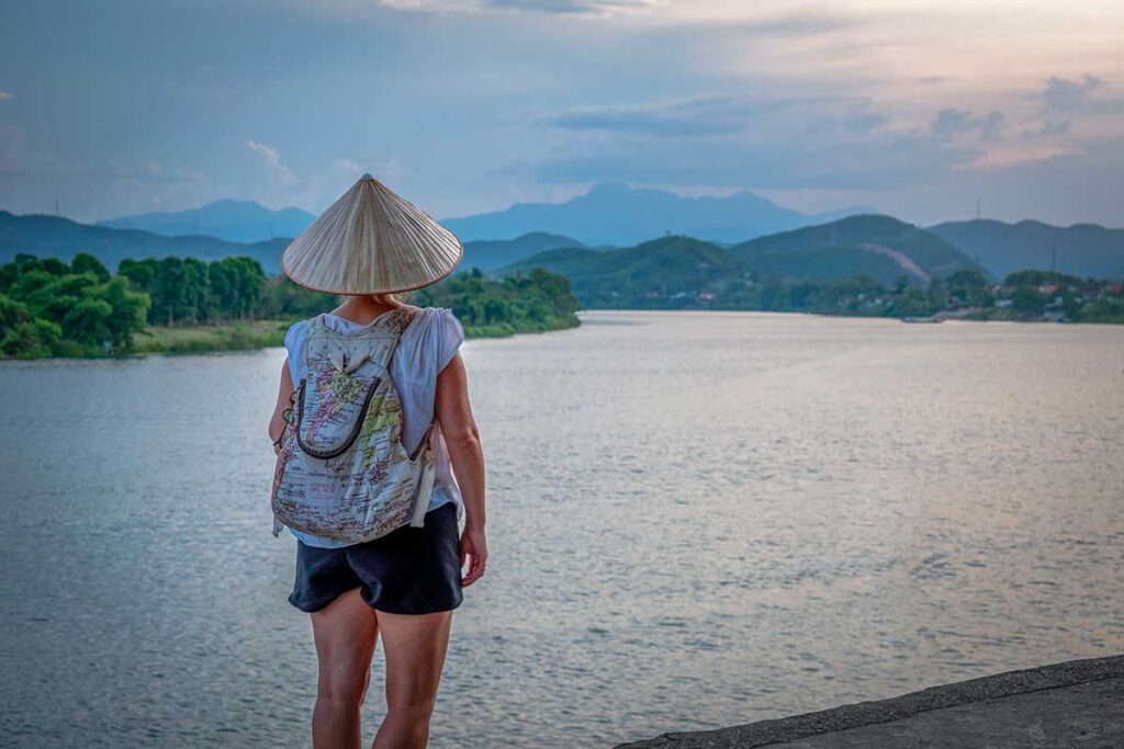 A tourist woman with conical hat is overlooking the Perfume River near Hue