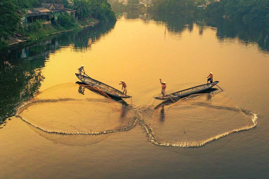 Perfume River during sunrise with local fishermen throwing nets in the water for fishing