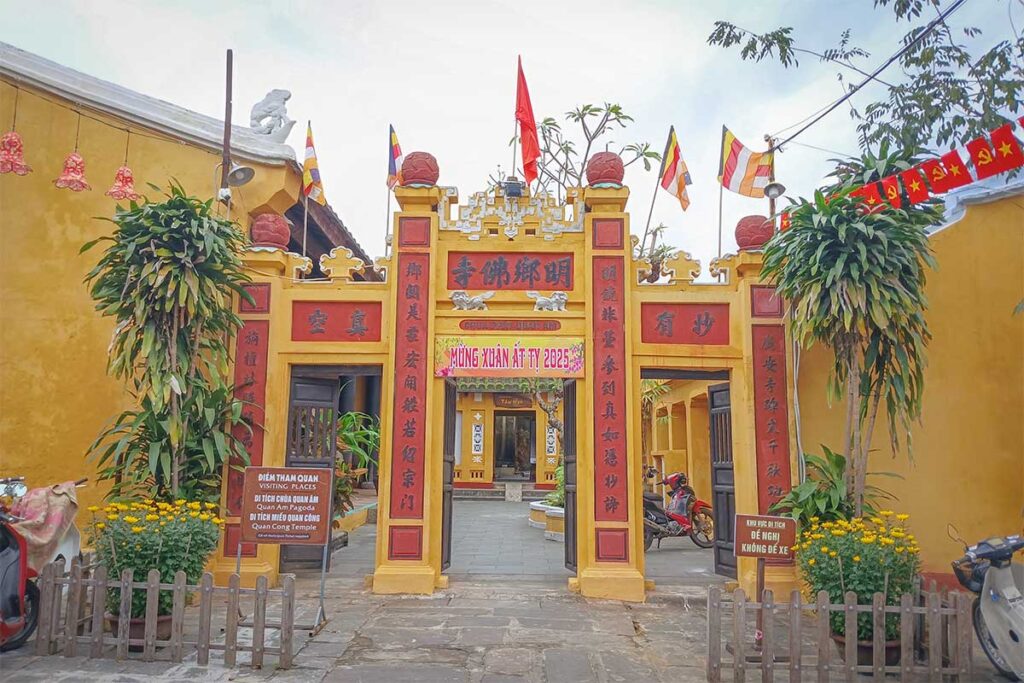 Entrance gate of Quan Am Pagoda in Hoi An decorated with red calligraphy panels and festive New Year banners – traditional Buddhist temple doorway in the Ancient Town.