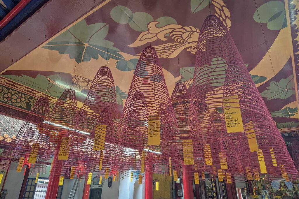 Incense coils hanging from temple ceiling in Hoi An – Rows of spiral incense coils with prayer tags suspended inside Quan Cong Temple, creating a spiritual atmosphere.