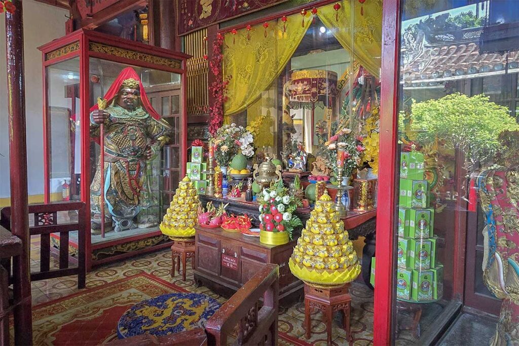 Sacred altar with warrior statue and offerings inside Quan Cong Temple