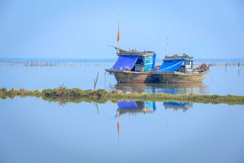 Small fishing boat with roof made of canvas drifting on Tam Giang Lagoon