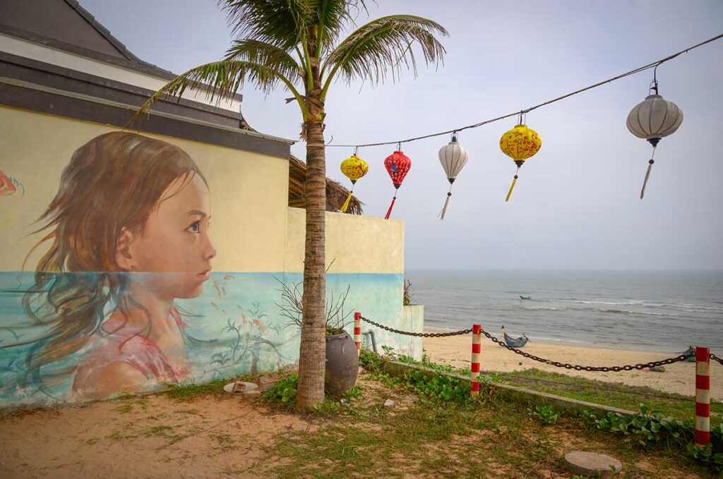 Vivid mural of a little girl gazing toward the sea, decorating a seaside wall in Tam Thanh Mural Village.