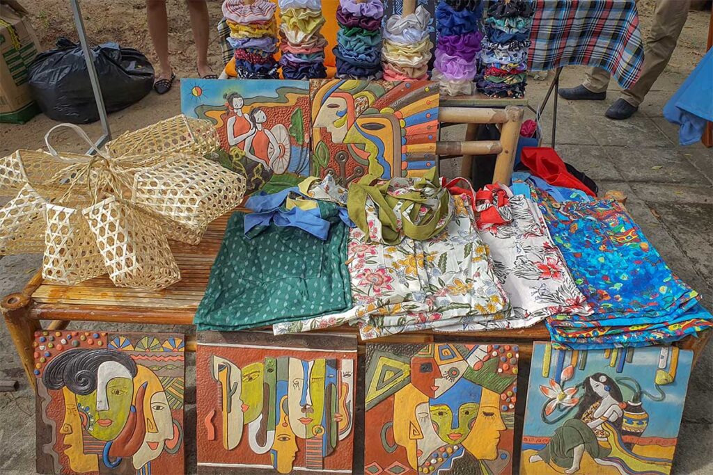 Colorful handmade crafts, paintings, and fabric bags for sale at Tan Thanh Flea Market in Hoi An