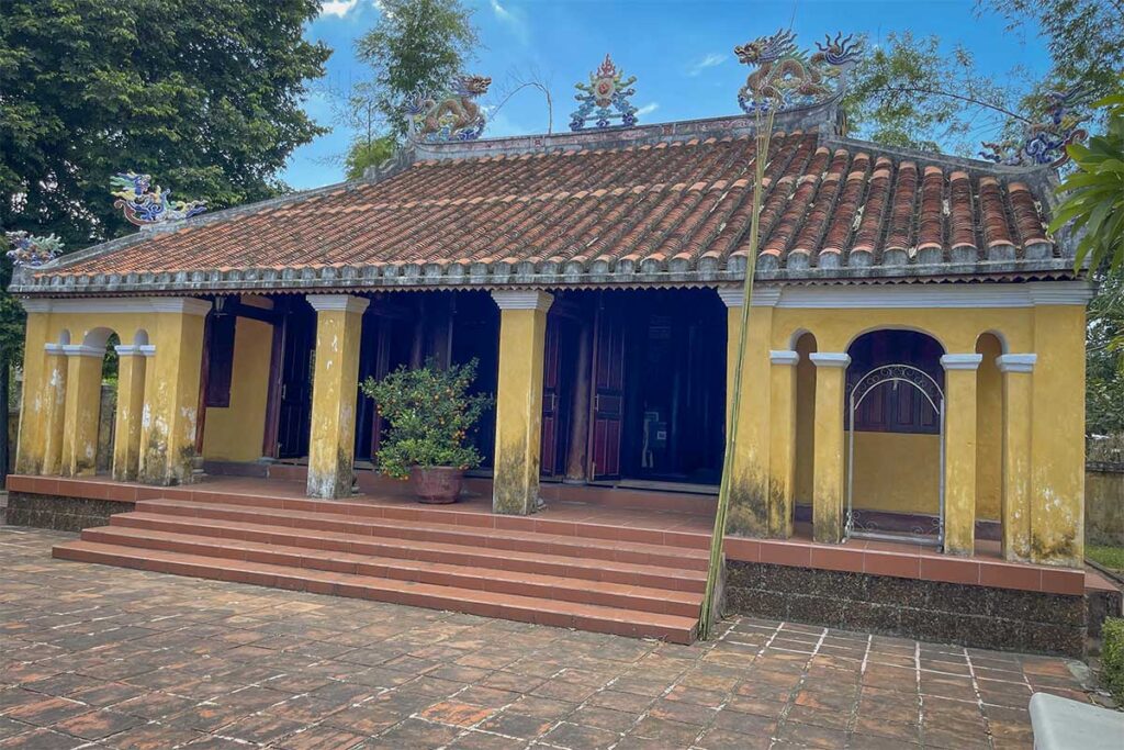 Front view of Thach Tan Communal House with yellow walls, red-tiled roof, and dragon motifs, an important heritage site linked to Ky Anh Tunnels in Quang Nam.
