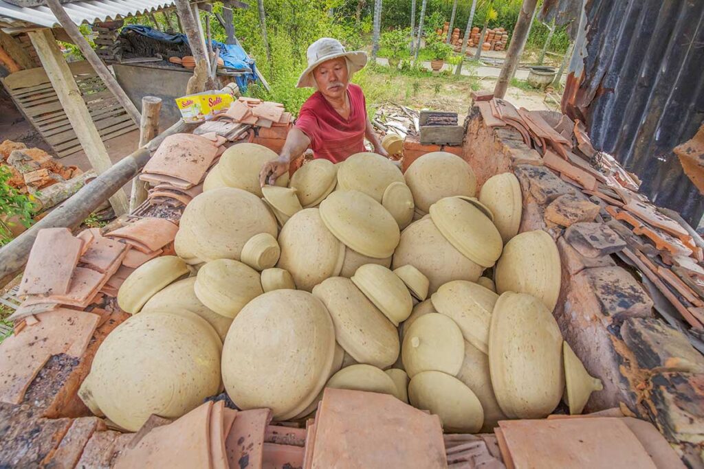 Vietnamese craftsman loading clay pots into a kiln at Thanh Ha Pottery Village in Quang Nam Province