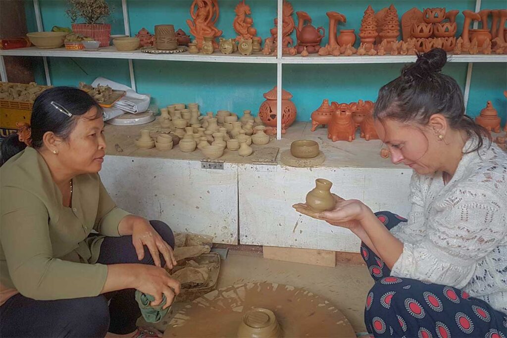 Traditional pottery lesson in Thanh Ha village – A visitor learns to shape clay on a pottery wheel under the guidance of a local artisan in Hoi An.