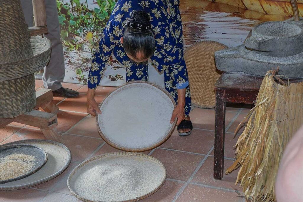An elderly woman is showing traditional agriculture techniques inside Thanh Toan Museum