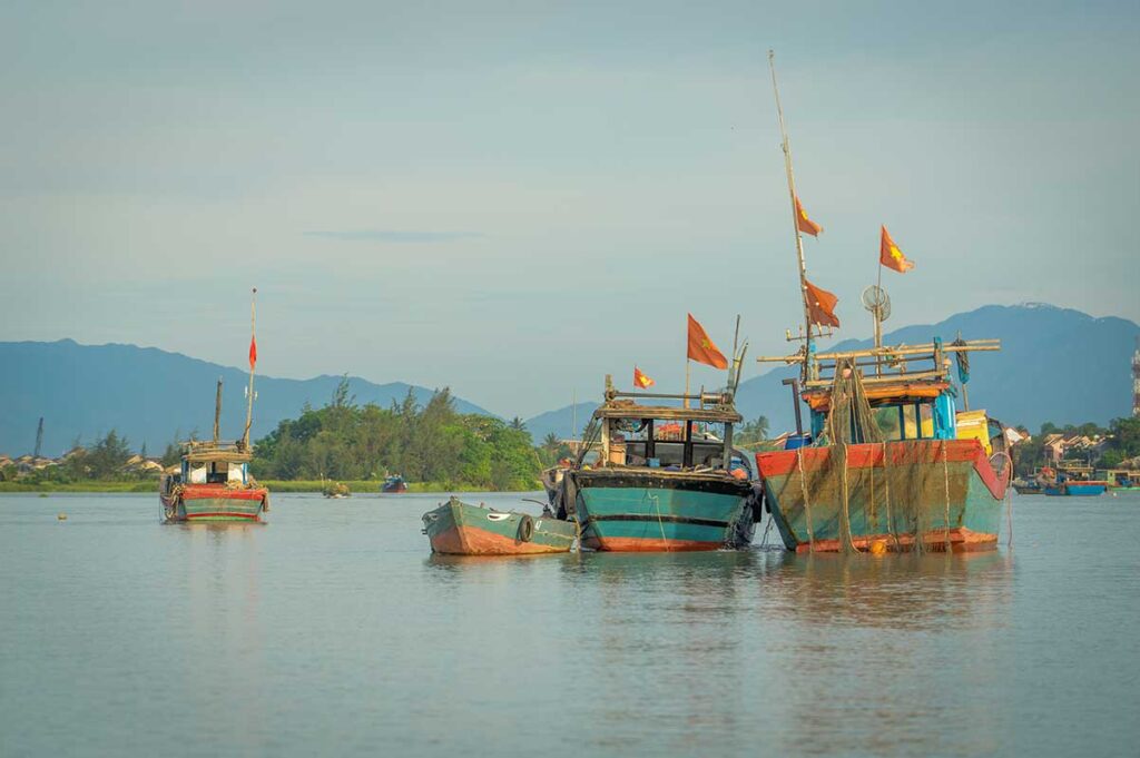 Fishing boats anchored along the Thu Bon River – authentic local scenery during a river boat tour in Hoi An.