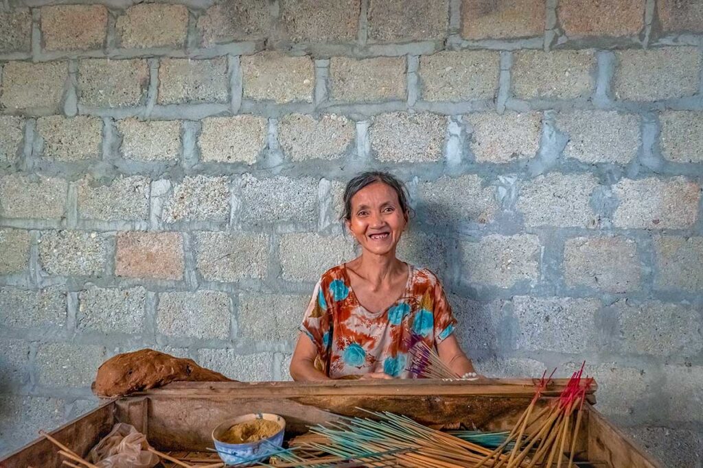 An elderly woman sitting in her home making incense in Thuy Xian Village