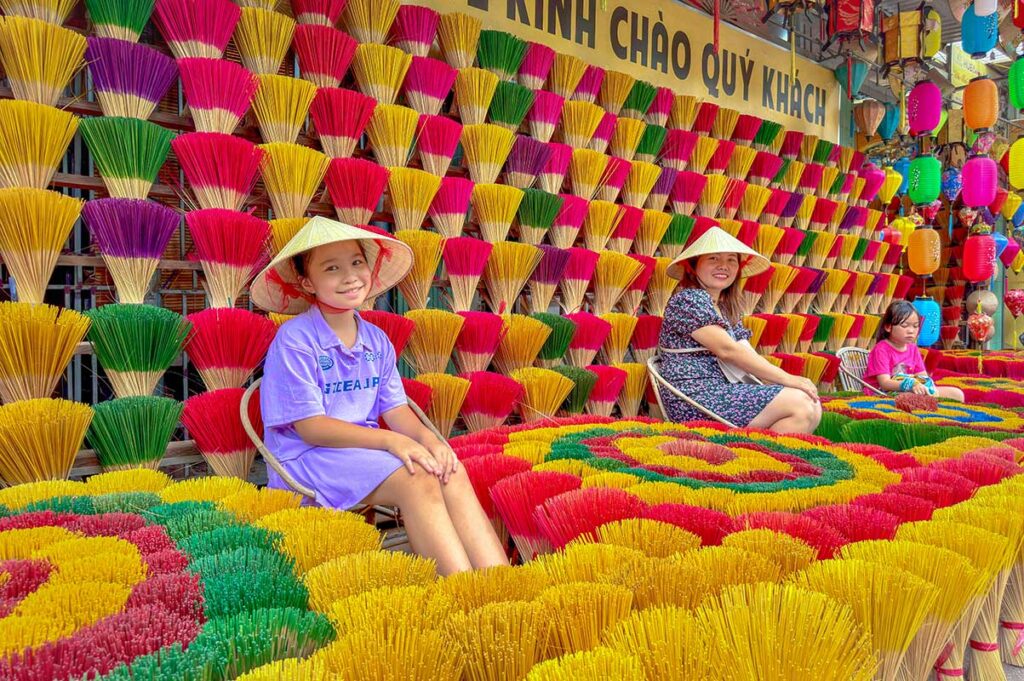 Local tourists with conical hats sitting between incense sticks for a photo at the incense village of Hue 