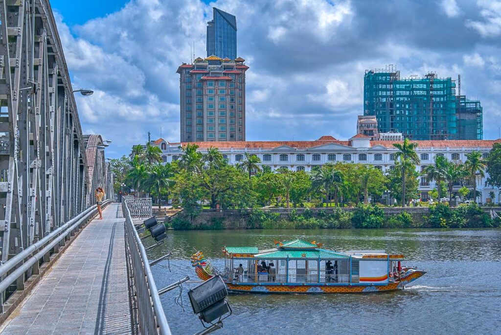A dragon boat is riding below the Trang Tien Bridge