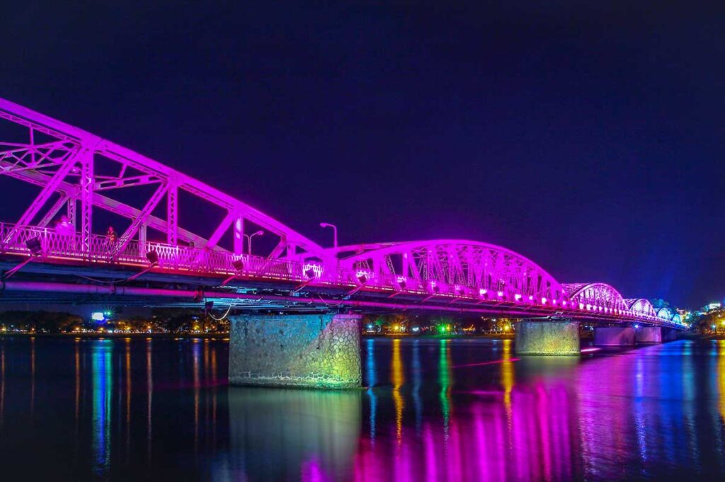 The Trang Tien Bridge at night with beautiful pink colors seen from the walking promenade along the Perfume River in Hue