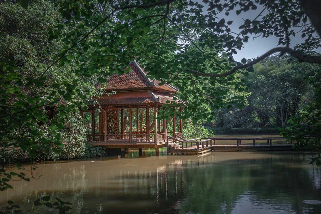 A covered water pavilion, connected by a zigzag bridge over a fish/lily pond