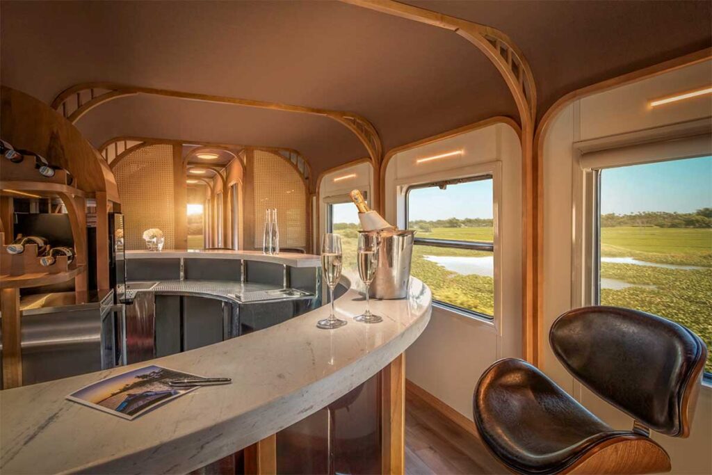 Bar area inside The Vietage luxury train in Vietnam with drinks and countryside views through large windows during the journey