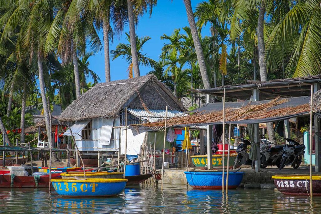 Colorful round basket boats lined up along the riverbank in Cam Thanh Village near Hoi An, ready for coconut forest tours.