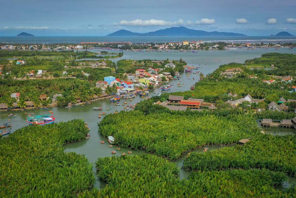 Panoramic aerial view of Cam Thanh Coconut Village with dense palm forests, waterways, and round basket boats near Hoi An.