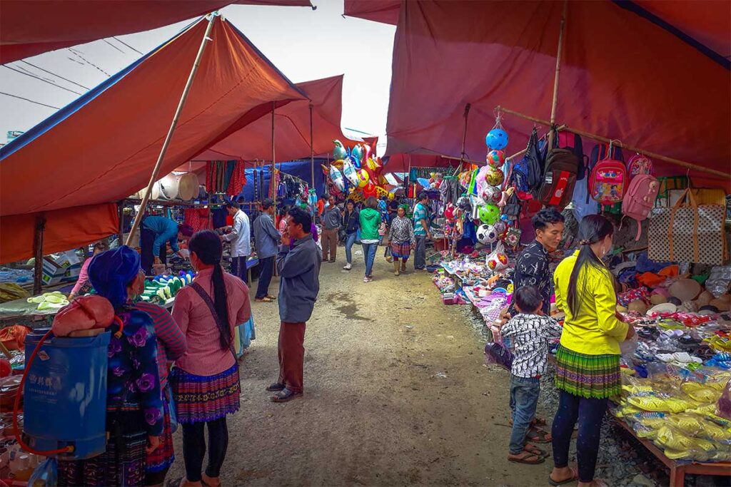 Stalls lining up on both sides with local ethnic people browsing and chatting at the Cao Son Market
