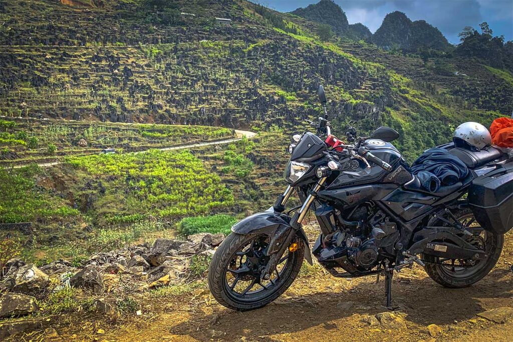 A rented large motorbike parked on a road between the mountains of Ha Giang