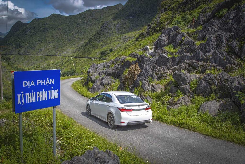 A white rented car driving through the mountains of Ha Giang