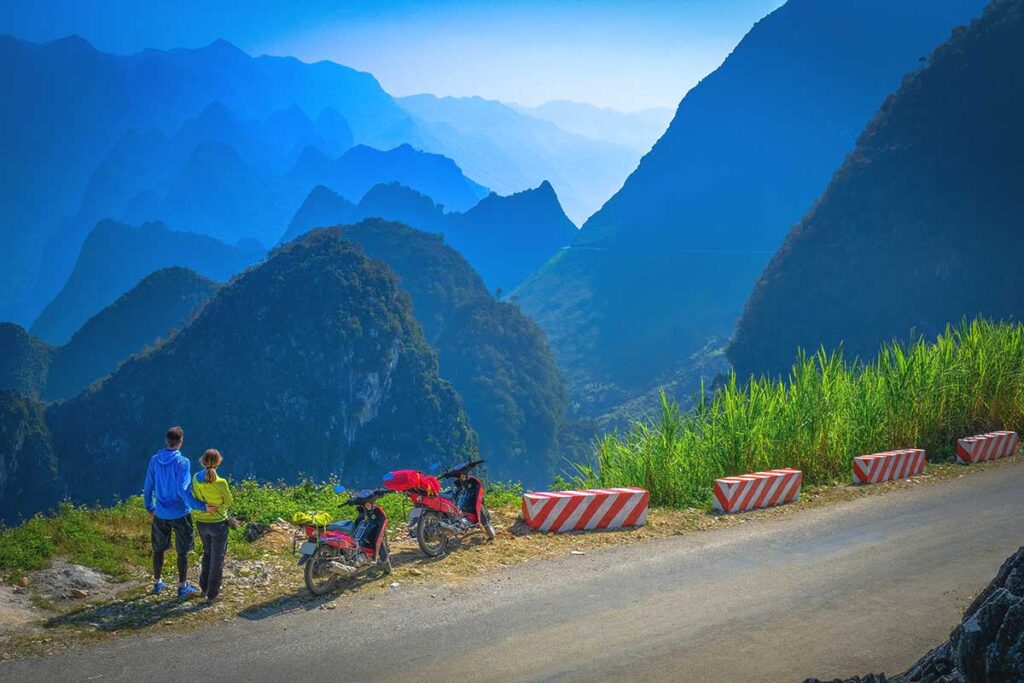 Two people driving the Ha Giang Loop by motorbike on a stunning mountain pass