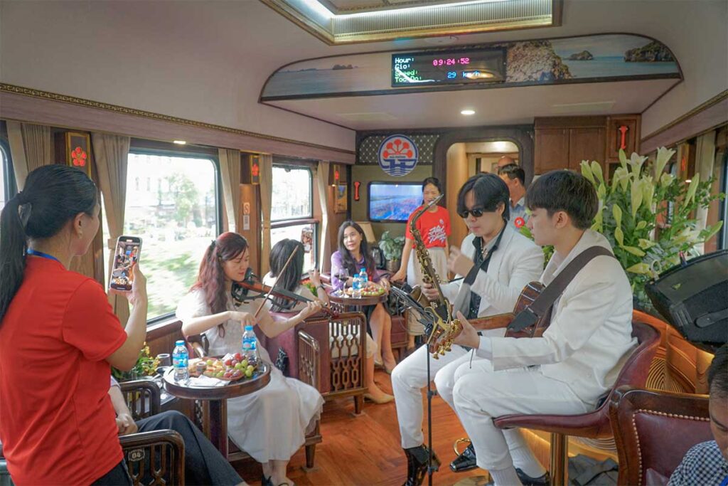 Passengers enjoying live music performance inside a tourist train from Hanoi to Hai Phong, showing the unique onboard experience in Vietnam