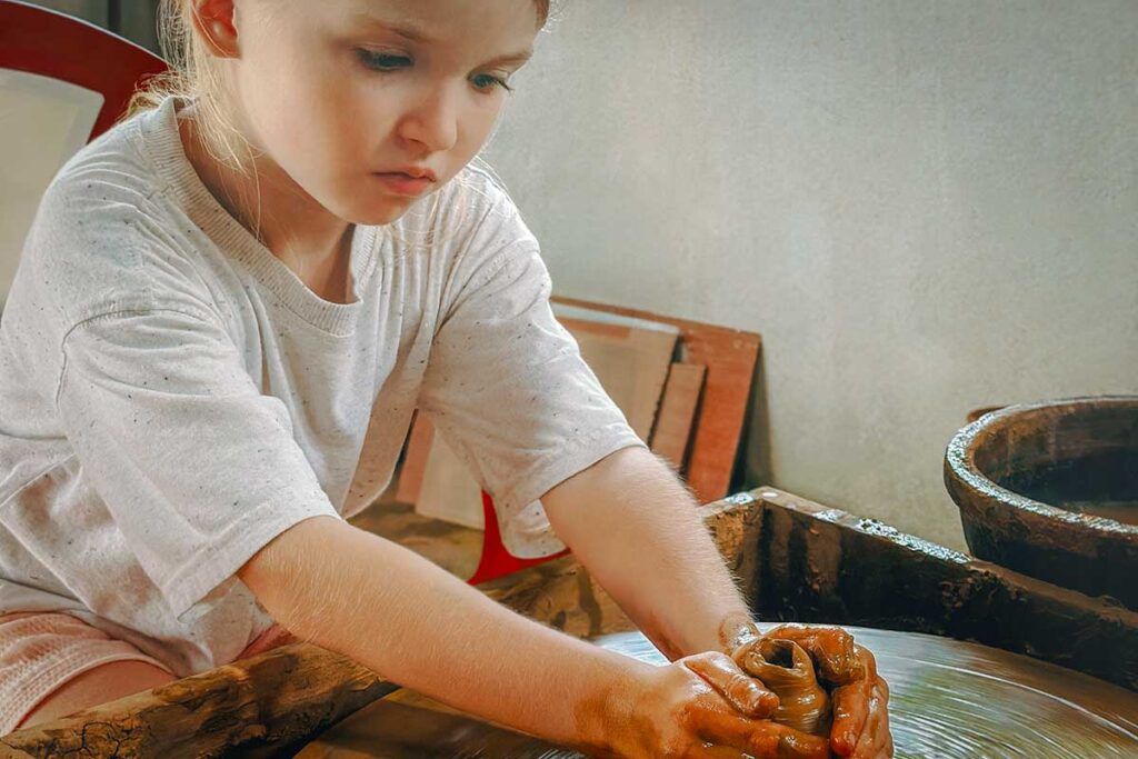 Child learning pottery at a hands-on workshop in Hoi An — a family-friendly souvenir experience and one of the best activities to enjoy Hoi An with kids.