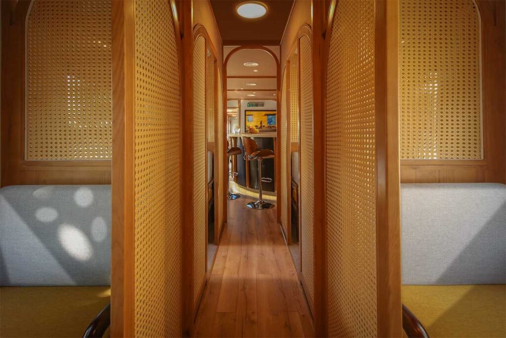 Elegant interior corridor of The Vietage luxury train in Vietnam, featuring wooden design, private cabins, and premium seating